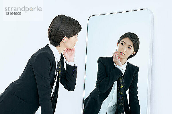 Junge japanische Frau schaut in den Spiegel