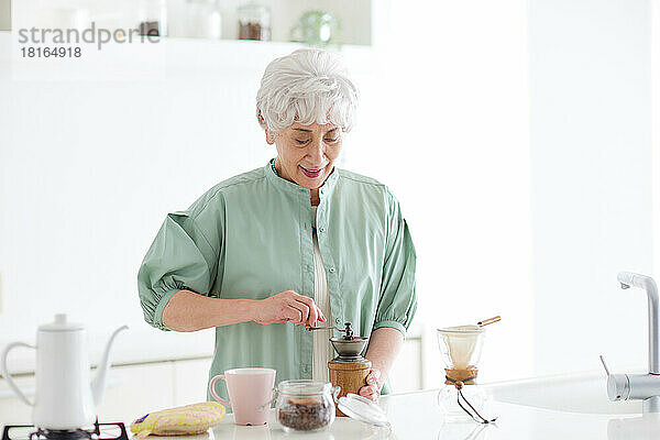 Ältere japanische Frau mahlt Kaffeebohnen