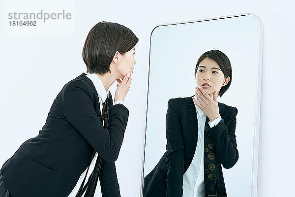 Junge japanische Frau schaut in den Spiegel