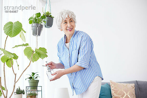 Japanische Seniorin gießt Pflanzen