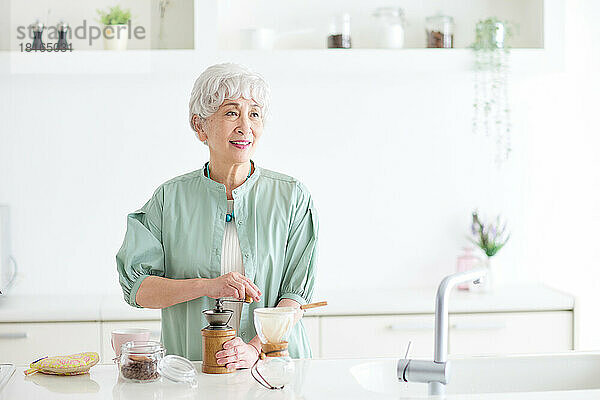 Ältere japanische Frau mahlt Kaffeebohnen