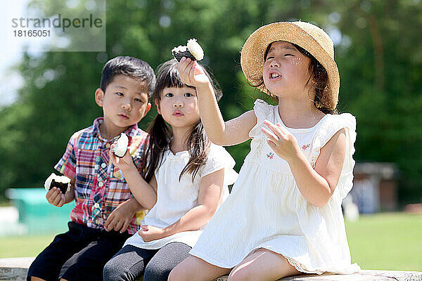 Japanische Kinder essen in einem Stadtpark
