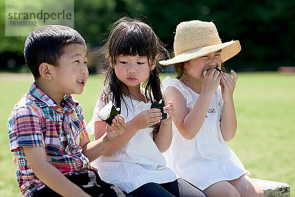 Japanische Kinder beim Essen in einem Stadtpark