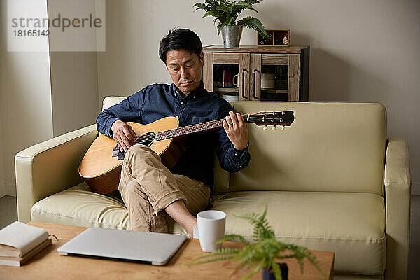 Japanischer Mann spielt akustische Gitarre