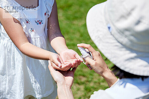 Japanisches Kind benutzt Händedesinfektionsmittel in einem Stadtpark