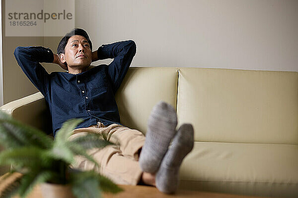 Japanischer Mann entspannt sich auf dem Sofa