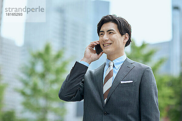 Japanischer Geschäftsmann spricht auf Smartphone