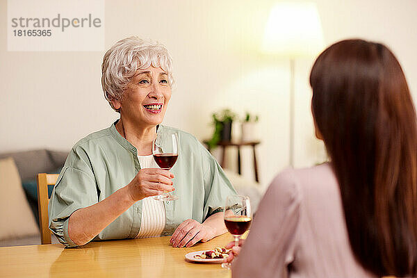 Japanische Senioren und junge Frauen genießen Wein zu Hause