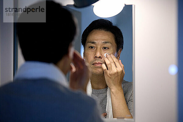 Japanischer Mann trägt Gesichtscreme auf