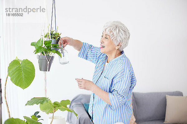 Japanische Seniorin beim Gießen von Pflanzen