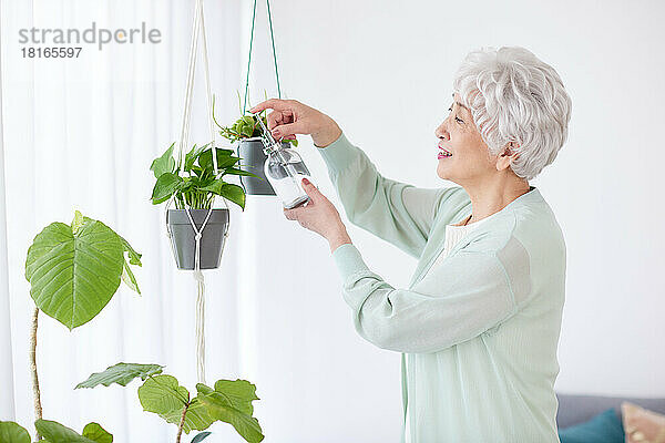 Japanische Seniorin gießt Pflanzen