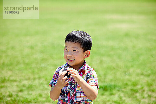 Japanisches Kind isst in einem Stadtpark