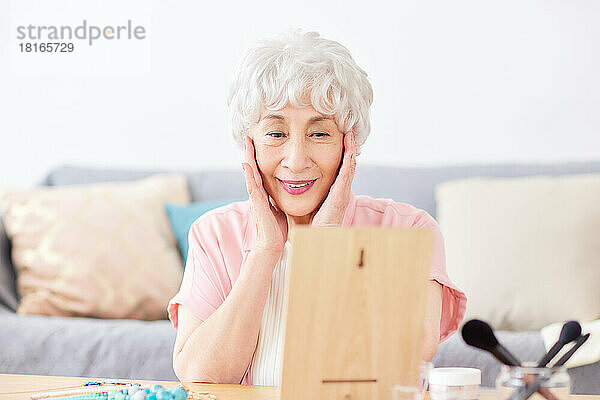 Japanische Seniorin beim Blick in den Spiegel