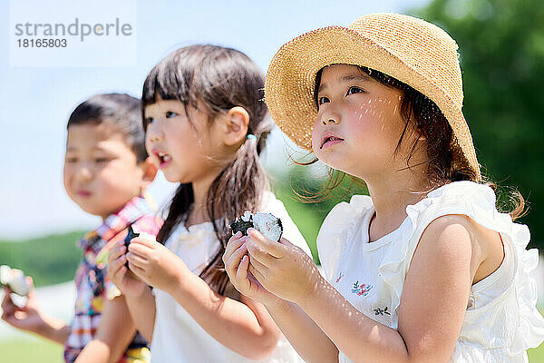 Japanische Kinder beim Essen in einem Stadtpark