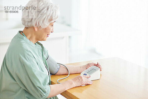 Japanische Seniorin beim Blutdruckmessen
