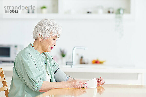 Japanische Seniorin beim Blutdruckmessen