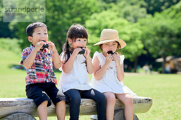 Japanische Kinder beim Essen in einem Stadtpark