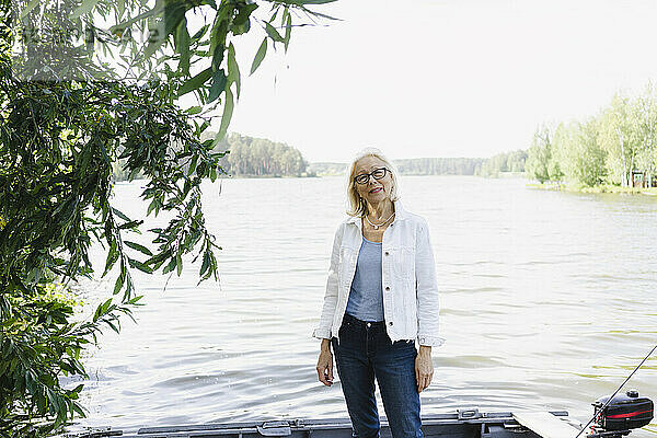 Ältere Frau steht im Motorboot auf dem See