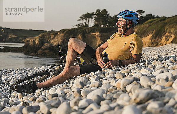 Glücklicher Mann mit Helm entspannt am Strand