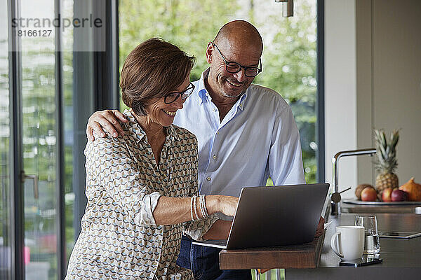 Glückliches älteres Paar  das zu Hause gemeinsam einen Laptop benutzt