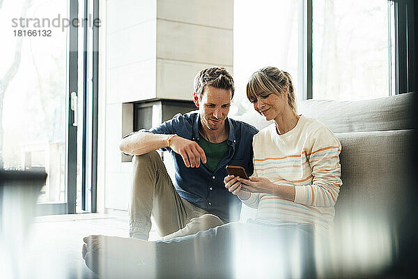 Werdendes Paar  das zu Hause sein Smartphone teilt
