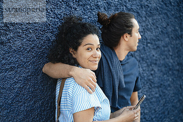 Lächelnde Frau mit Smartphone neben ihrem Freund