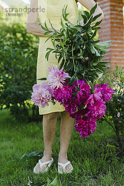 Frau hält frischen Blumenstrauß im Garten