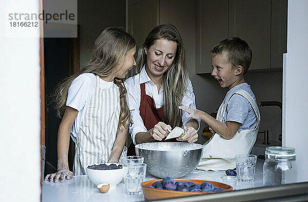 Fröhliche Kinder helfen Mutter beim Kochen zu Hause