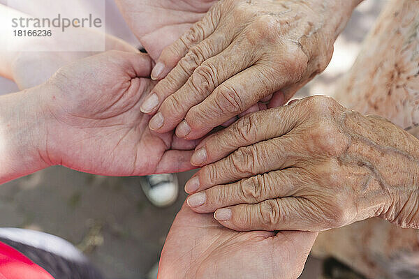 Ältere Frau hält die Hände ihrer Enkelin und Urenkelin
