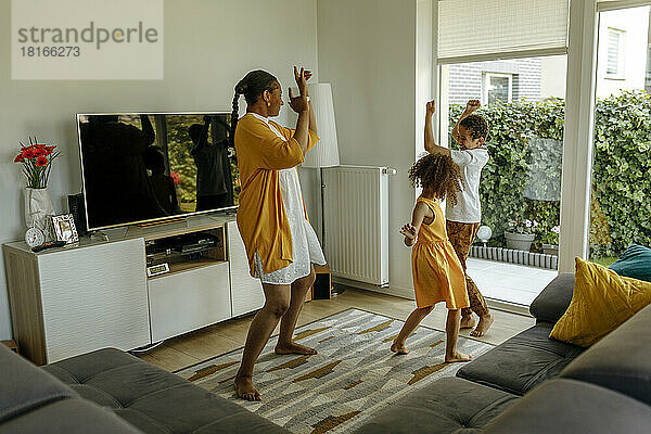 Glückliche Mutter mit Kindern  die im Wohnzimmer tanzen