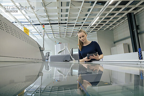 Junge Geschäftsfrau mit Tablet-PC untersucht 3D-Druckmaschine in der Industrie