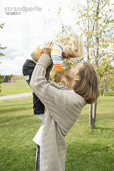 Glückliche Frau spielt mit Sohn im Park