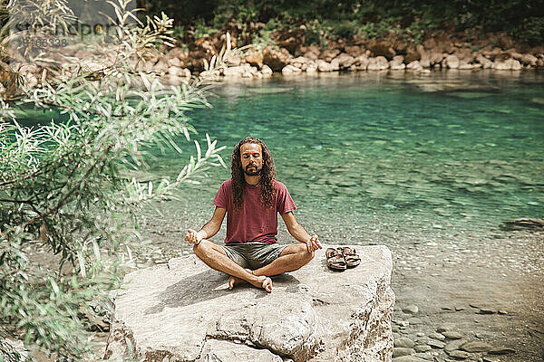 Junger Mann meditiert auf einem Felsen vor dem Tara-Fluss