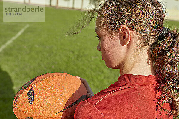 Mädchen hält Rugbyball an sonnigem Tag