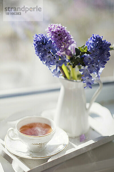 Heißer Tee in einer Vintage-Tasse neben einer Blumenvase zu Hause