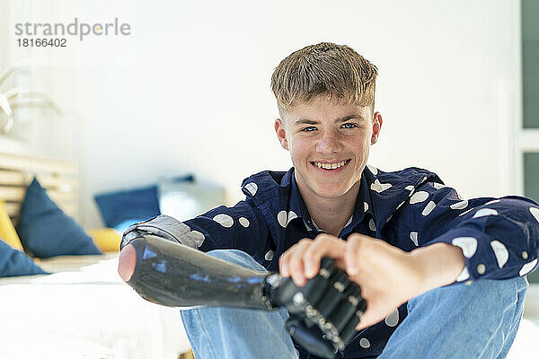 Lächelnder Junge mit Armprothese sitzt neben Möbeln