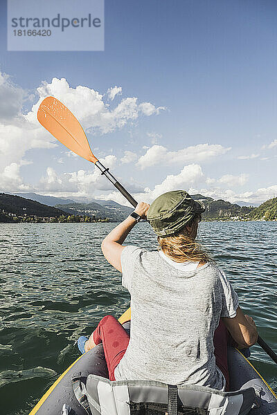 Frau fährt an einem sonnigen Tag Kajak am See