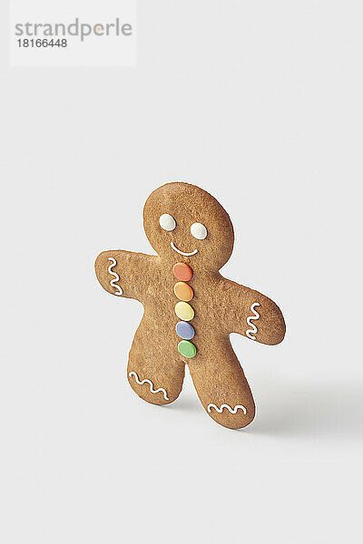 Decorated gingerbread man standing against white background
