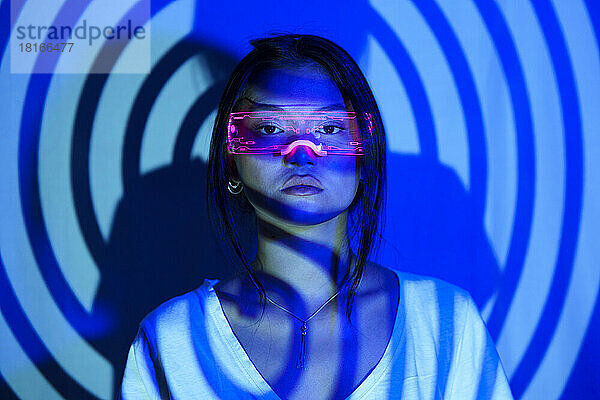 Spiral shadow on young woman wearing LED futuristic glasses