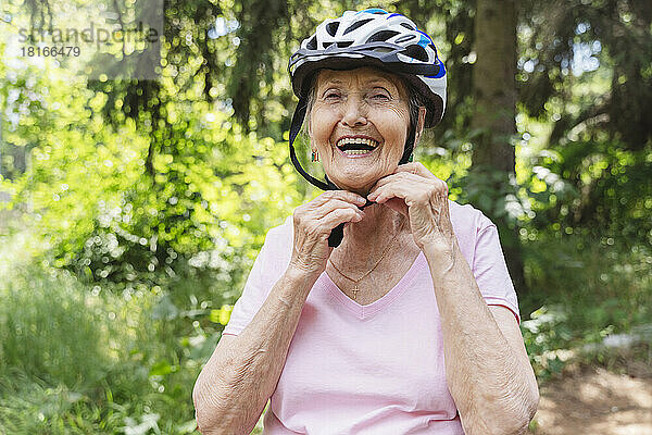 Glückliche ältere Frau mit Fahrradhelm im Park