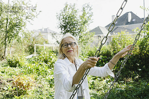 Ältere Frau hält Schaukelkette im Garten