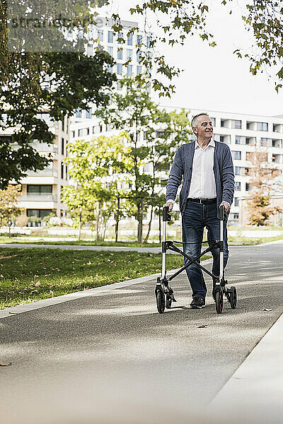 Glücklicher älterer Mann  der mit Gehhilfe auf dem Fußweg läuft