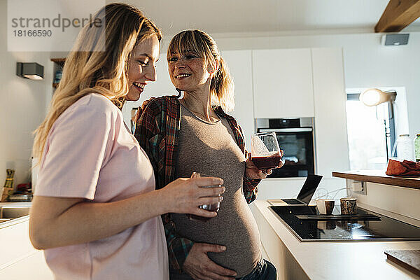 Schwangere Frau genießt zu Hause einen Drink mit ihrer Schwester