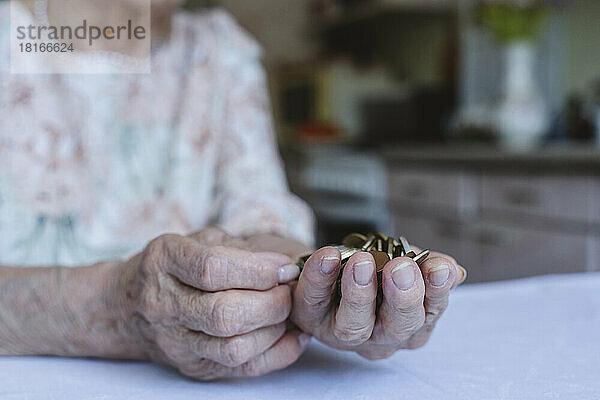 Ältere Frau hält zu Hause Münzen in der Hand