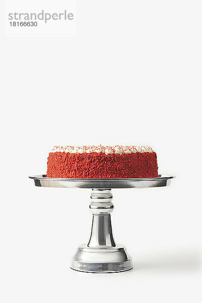 Köstlicher hausgemachter roter Samtkuchen auf silbernem Kuchenständer vor weißem Hintergrund
