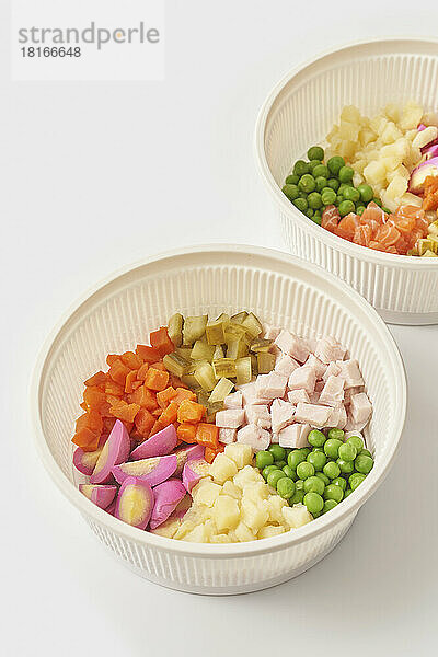 Set of bowls with ingredients for olivier salad on white background