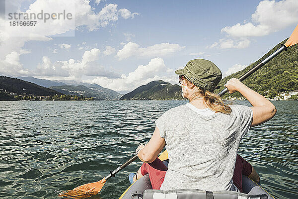 Reife Frau fährt an einem sonnigen Tag Kajak am See