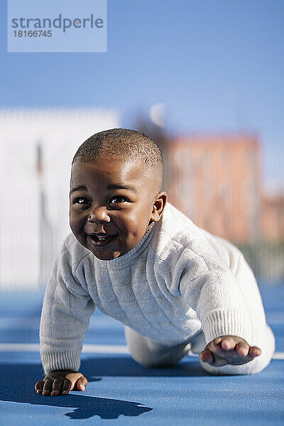 Happy cute baby crawling on sports court
