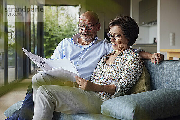 Lächelnder Mann und Frau lesen zu Hause Dokumente