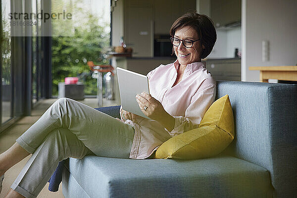 Glückliche Frau  die zu Hause einen Tablet-PC benutzt